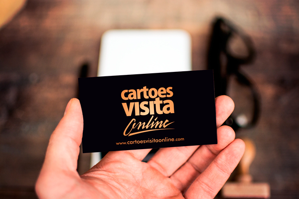 Mão segurando cartão profissional com design moderno, representando serviços e vantagens de cartão de visita online para divulgação de contatos e presença digital.