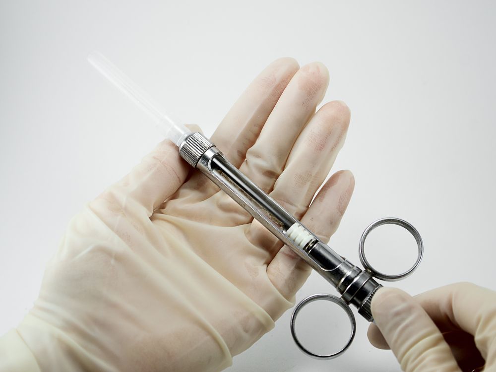 Profissional da saúde segurando seringa odontológica utilizada para aplicação de anestesia em procedimentos clínicos e cirúrgicos.